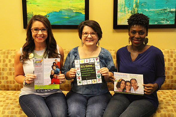 Three ladies holding marketing materials